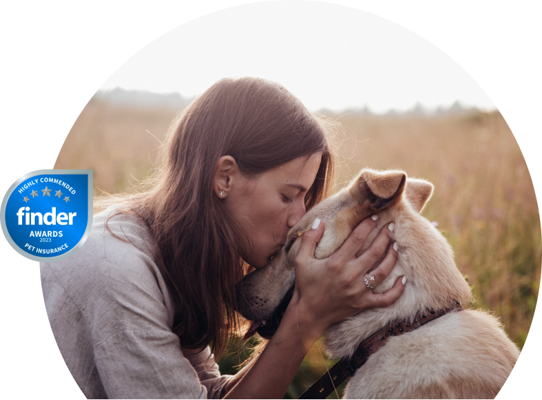 Woman kissing her dog in a field.
